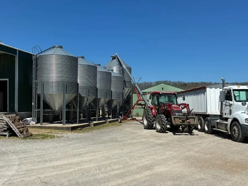 A grain truck and tractor parked at the loading side of the Duck It Farm mill