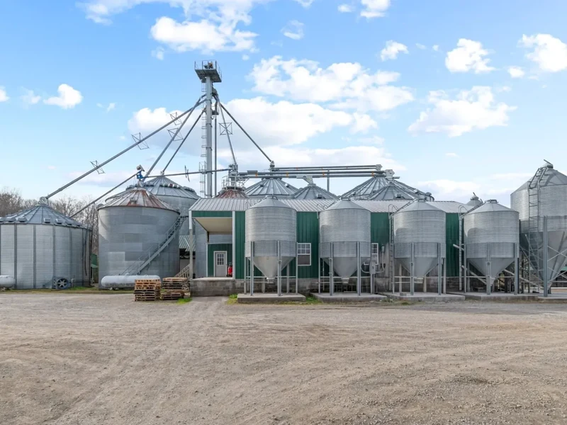 Duck It Farm's feed mill in Centerville, Tennessee: a row of steel grain bins and augers beside a green and white mill building