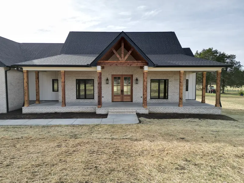Custom home built by Outback Construction: brick facade, peaked roof with exposed timber beams, covered front porch
